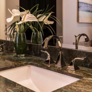 a bathroom sink with mirror and white lilies in a vase